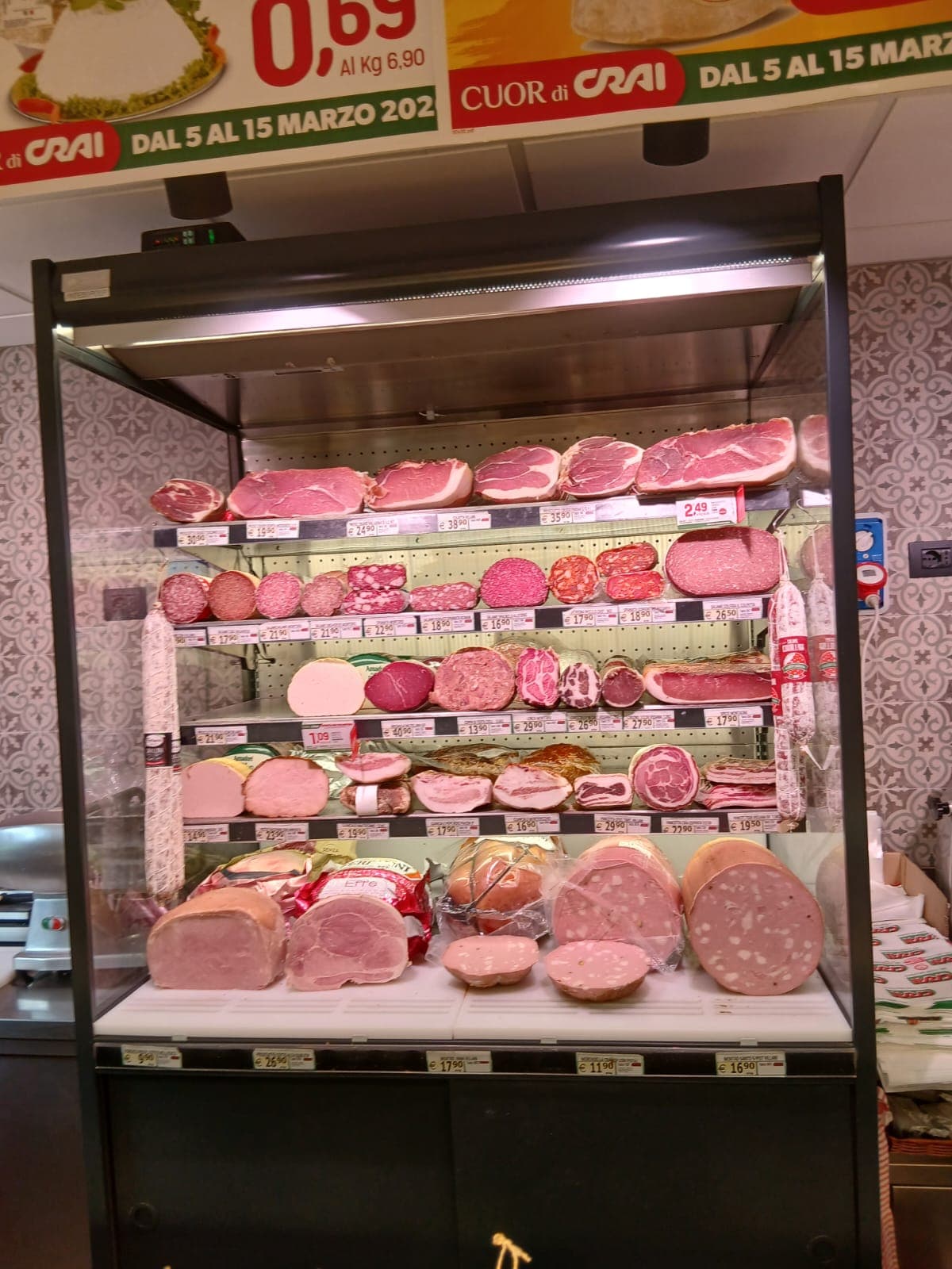 Vetrina refrigerata con assortimento di salumi, prosciutti e mortadella in un banco gastronomia.