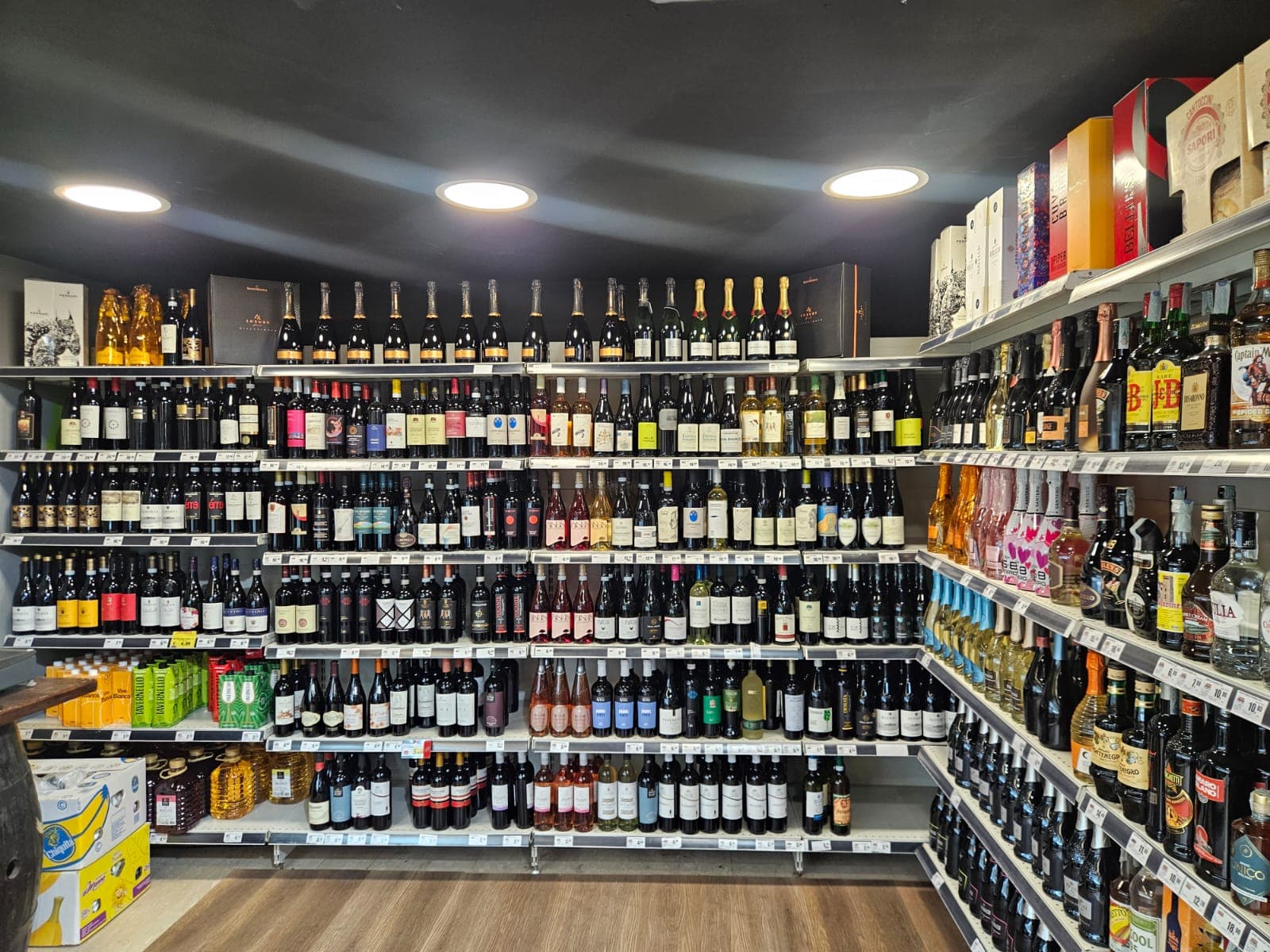 Scaffali di un negozio pieni di numerose bottiglie di vino, champagne e vari liquori.